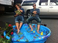 two men sitting on top of an inflatable pool