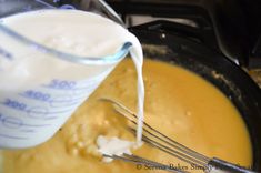 a person pouring milk into a pot filled with batter and cheesecakes on the stove