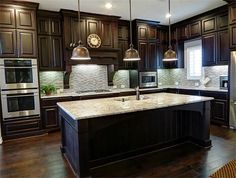 a kitchen with dark wood cabinets and marble counter tops