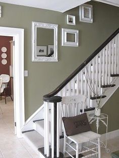 an entry way with stairs and pictures on the wall, along with a white chair