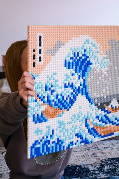 a woman is holding up a large lego art piece that has been made to look like a wave