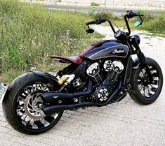 a black motorcycle parked on the side of a road next to tall grass and flowers