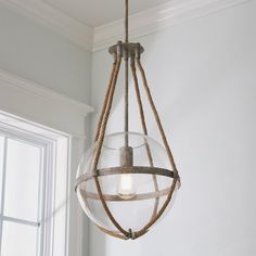 a light fixture with rope wrapped around it hanging from the ceiling in front of a window