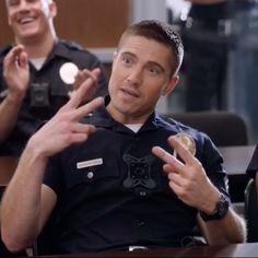 two men in police uniforms are talking to each other while one man holds out his hands