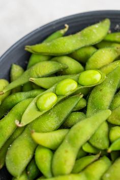 a bowl filled with green beans sitting on top of a table