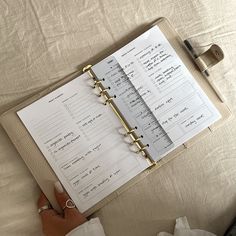 a person is holding a binder on top of a bed with papers attached to it