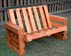 a wooden bench sitting in the grass near a fence