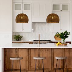 two hanging lights above a kitchen island with stools