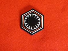 a star wars pin sitting on top of a red shirt with black and white trim