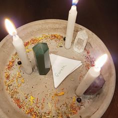 three candles are arranged in a circle on a plate with other items around the candle