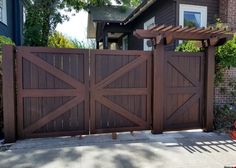 a wooden gate with an attached trellis on the side of a house next to a red fire hydrant