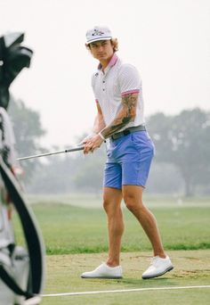 a man holding a golf club on top of a green field