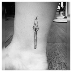 a black and white photo of a small tattoo on the ankle that has a long stick sticking out of it