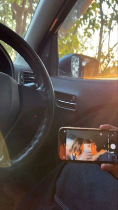 a person taking a selfie in the car with their cell phone while sitting on the driver's seat