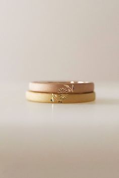 two gold wedding bands with small flowers on each band, set against a white background