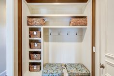 a white closet with two benches and baskets on the wall next to eachother