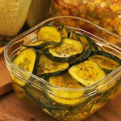 sliced zucchini in a plastic container sitting on a table next to other vegetables