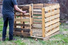 a man standing next to a pile of wooden pallets on top of a grass covered field