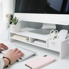 a person typing on a keyboard at a desk with a computer monitor and other items