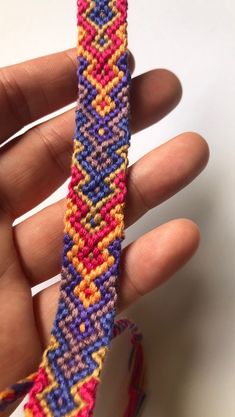 a hand is holding a colorful bracelet in it's left hand and the beading has been stitched together