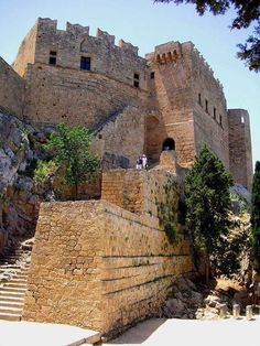 two people are standing on the top of a stone castle with steps leading up to it