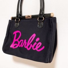 This is a Barbie handbag. The large pink logo on a black background is eye-catching. Excellent condition. A few scratches and scuffs, but no problems with use.      If you have any question about the condition, accessories, or anything about the product, Please feel free to message us. We are glad to answer all your concerns.   We promise to carefully pack and deliver it in a sturdy manner.   Please take a look at our other auctions. Also, please follow us. see more Barbie items.     Internation Barbie Bag For Women, Pink And Black Purse, Pink Rectangular Y2k Bag, Barbie Purse For Women, Barbie Tote, Barbie Handbag, Barbie Items, Purse Black, Girly Bags