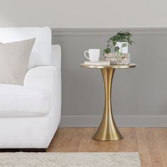 a white couch sitting next to a table with a coffee cup on top of it