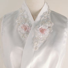 a white dress with pink flowers and pearls on the collar, along with an attached sash