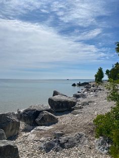 there is a bench on the beach by the water with rocks in front of it