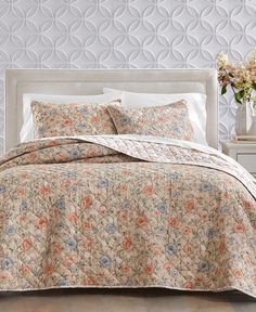 an image of a bedroom setting with flowers on the bed and wallpaper behind it