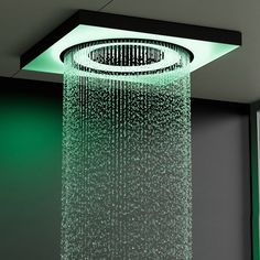 a shower head with water running down it's side and green walls behind it