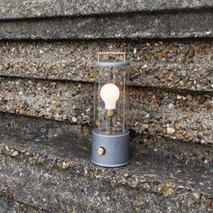 a light that is sitting on the ground next to some rocks and gravel with one light bulb glowing