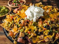 nachos with sour cream on top and salsa in the background