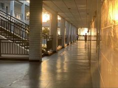 the sun is shining down on an empty hallway with railings and stairs leading up to two balconies