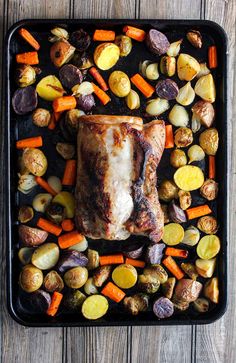 a roasting pan with pork, potatoes and carrots