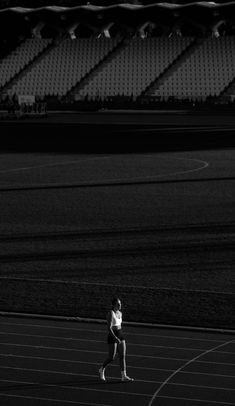 a woman running on a track in front of empty bleachers at night time