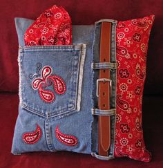 a red and blue pillow sitting on top of a couch next to a brown belt