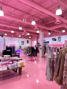 the inside of a clothing store with pink flooring and lights hanging from the ceiling