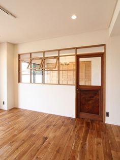 an empty room with wooden floors and windows in the wall, looking out onto a balcony