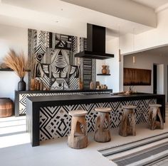 a kitchen with black and white tiles on the wall next to stools in front of an island