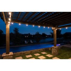 an outdoor patio with lights on the ceiling and lawn area next to it at night