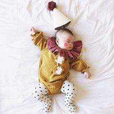 a baby is laying down with a party hat on its head and wearing polka dot pants