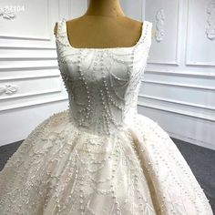 a white wedding dress with beading on the shoulders and neckline, sitting on a mannequin