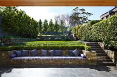 an outdoor seating area with steps leading up to the top of it and bushes on either side