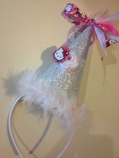 a hello kitty party hat with pink and white feathers