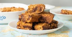 some brownies are stacked on top of each other in small white bowls and plates