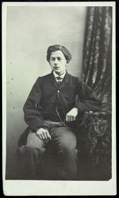 an old black and white photo of a man in a suit sitting on a chair