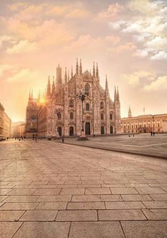 the sun is setting in front of an old cathedral