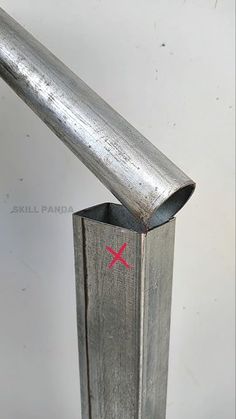 a metal pole with a red x painted on the side and a stick sticking out of it