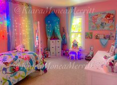 this is a bedroom with pink walls and colorful lights on the ceiling, bedding and curtains